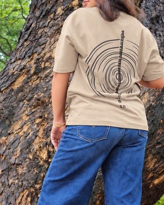 The Ashtanga Yoga T-shirt in Sandy Beige, worn outdoors, tightly cropped back view