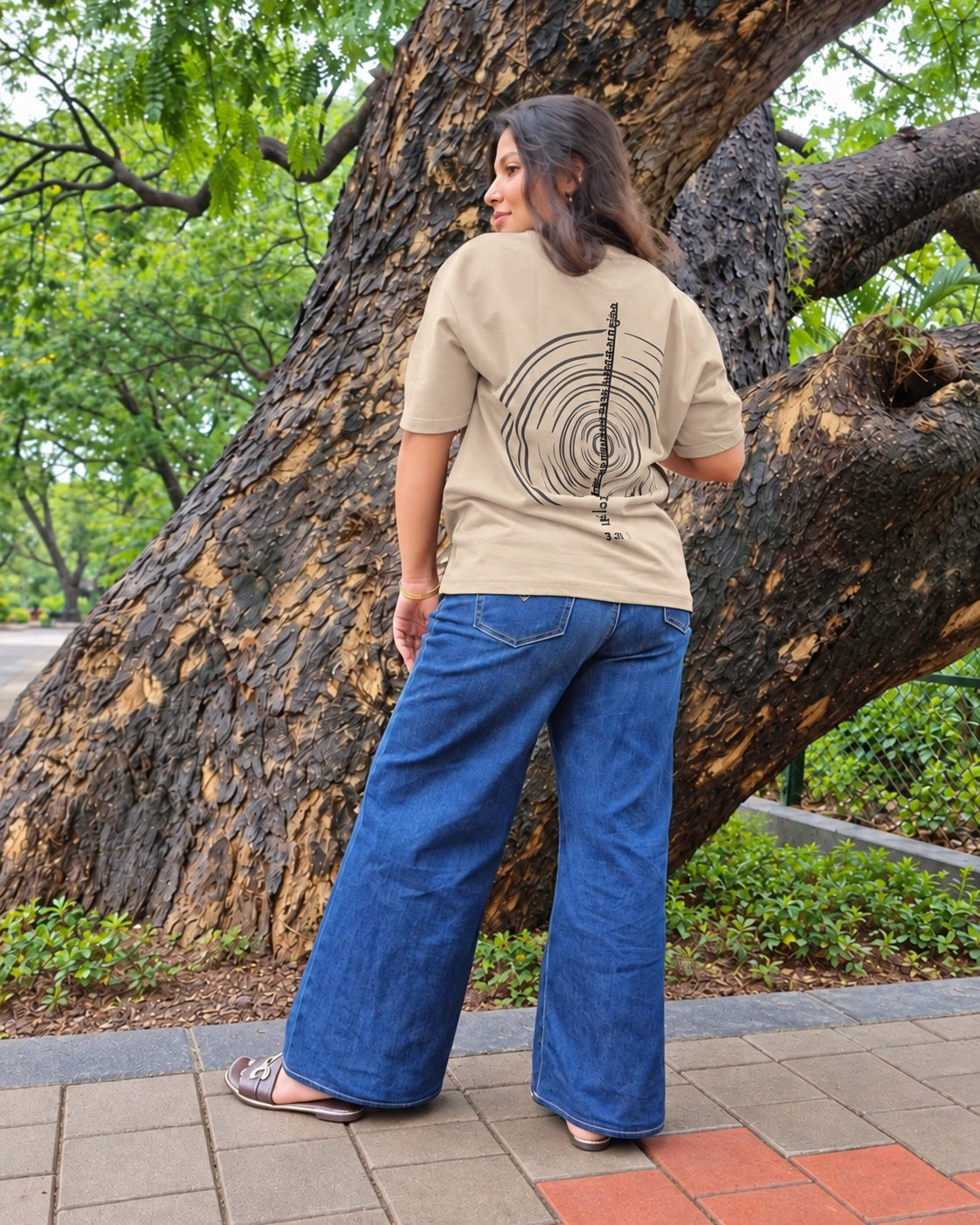 The Ashtanga Yoga T-shirt in Sandy Beige, worn outdoors, full-length back view